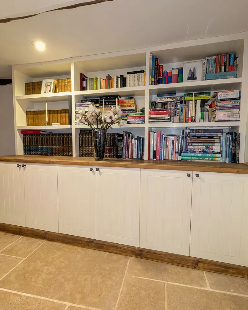 Built-in bookcases over cupboards with an oak top, built as one piece along a beamed wall