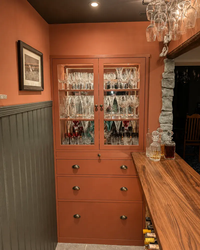 Terracotta-painted glazed drinks cabinet with internal lighting and walnut bar top
