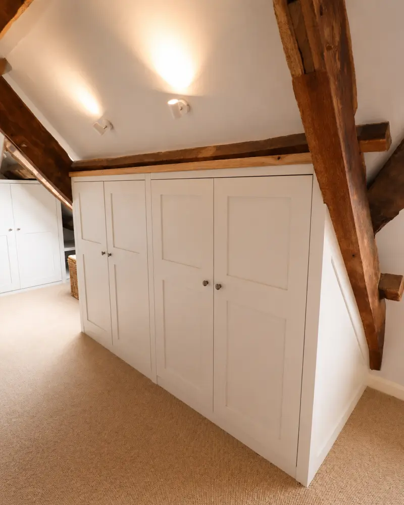 Fitted wardrobes in a loft bedroom, scribed to the sloping ceiling beside an exposed beam