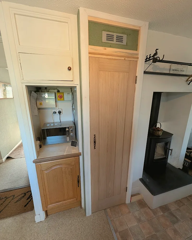 Oak boarded door made and hung in a cottage opening beside a wood burner