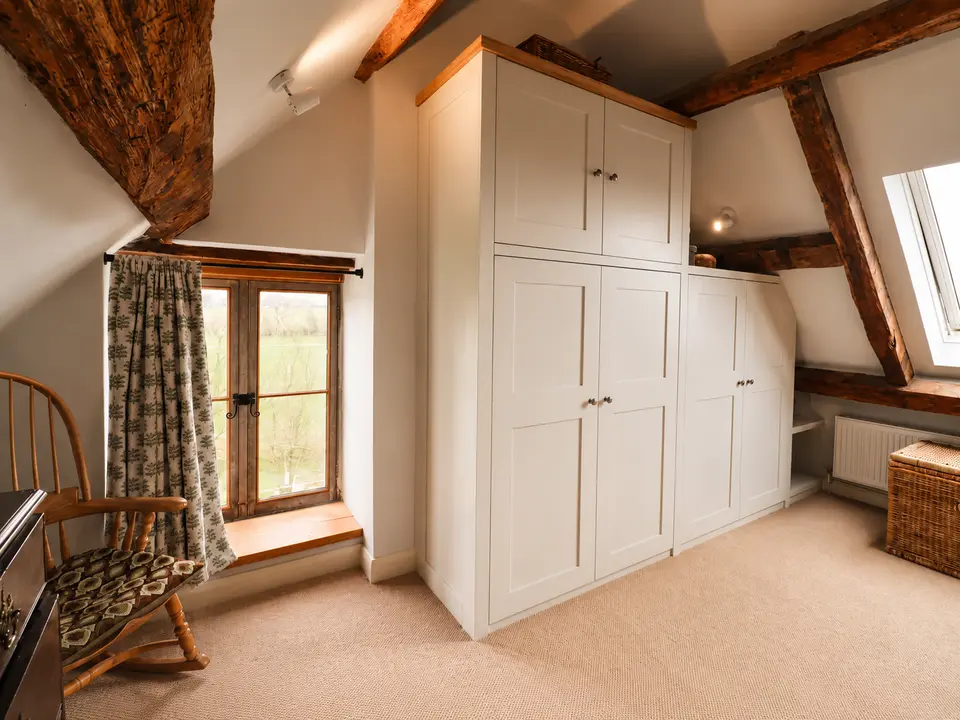 Fitted wardrobes built between exposed beams under a sloping ceiling