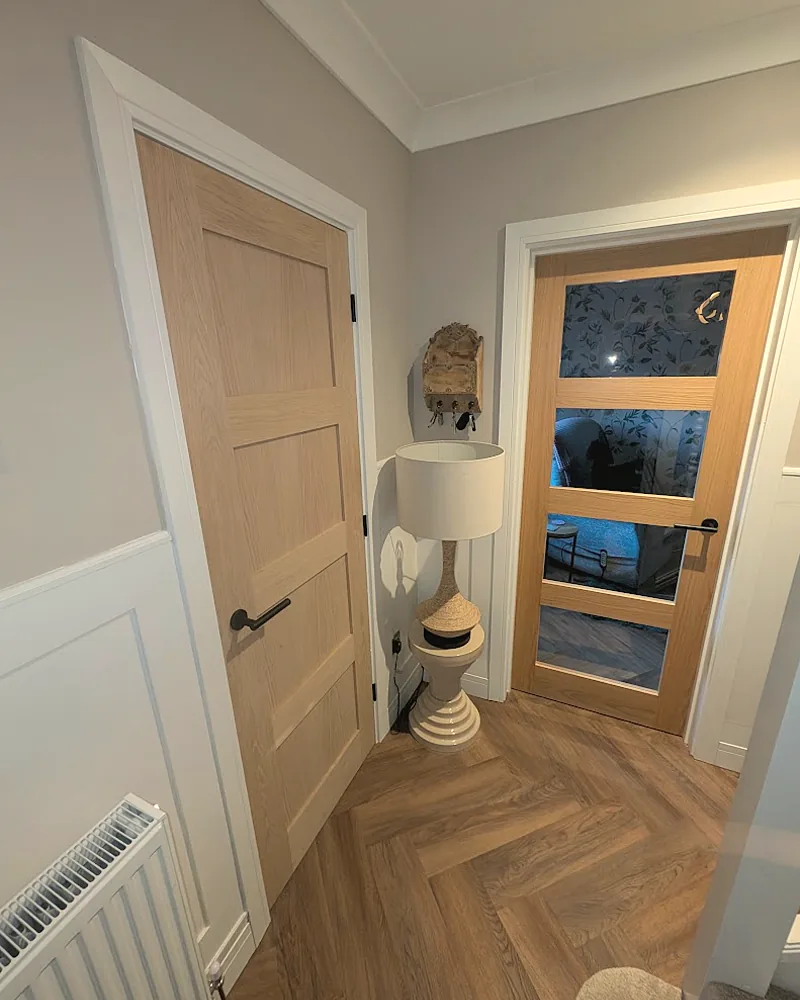 Oak panelled and glazed internal doors hung off a hallway with herringbone flooring