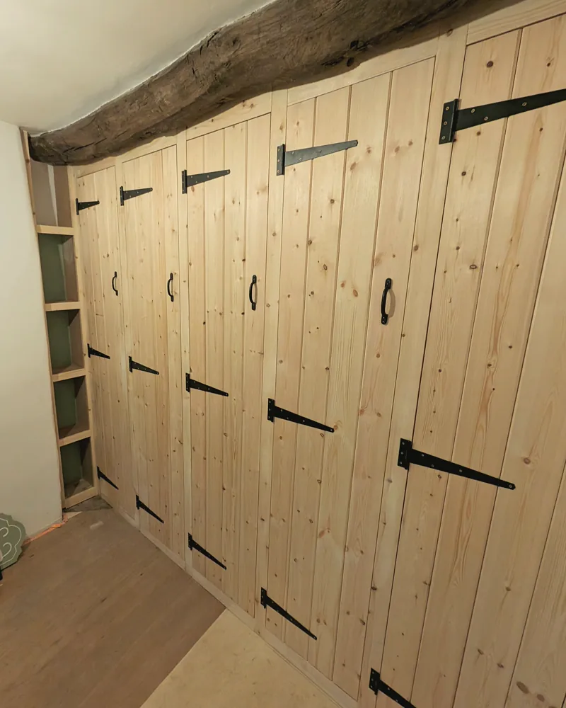 A run of pine fitted wardrobes scribed under an exposed oak beam