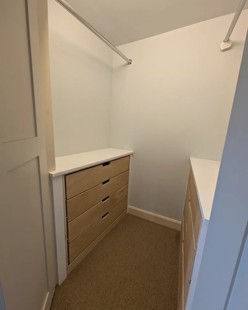 Walk-in wardrobe with oak-fronted drawers, hanging rails and open shelving