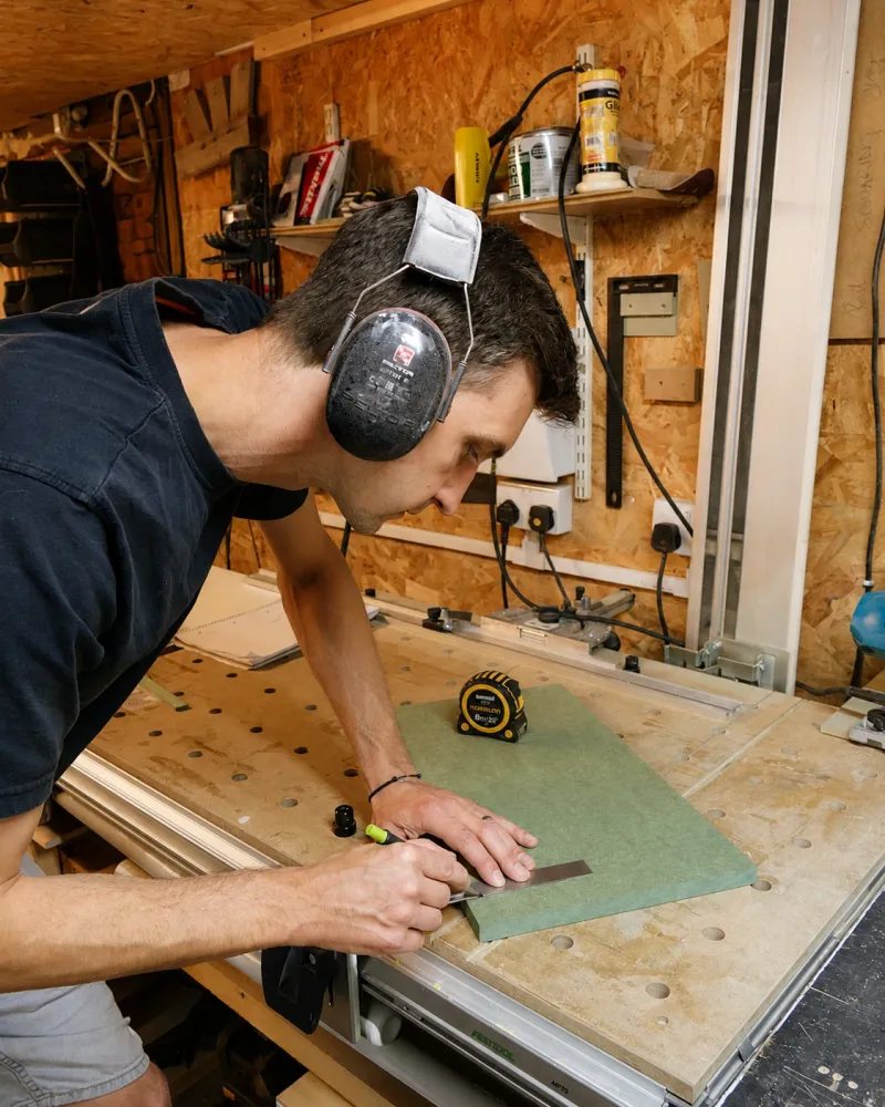 Will marking out a panel with a square and pencil at the workshop bench